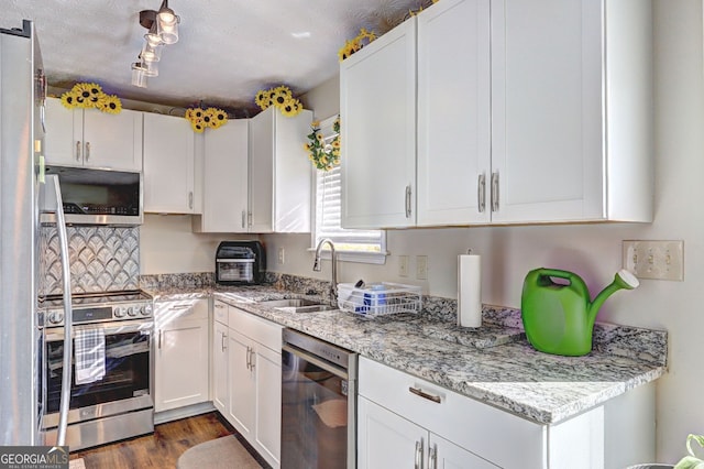 kitchen with white cabinetry, sink, stainless steel appliances, and light stone countertops