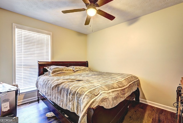 bedroom featuring ceiling fan, dark hardwood / wood-style flooring, and a textured ceiling