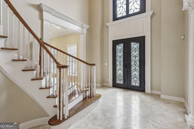 entrance foyer featuring a towering ceiling, decorative columns, and french doors