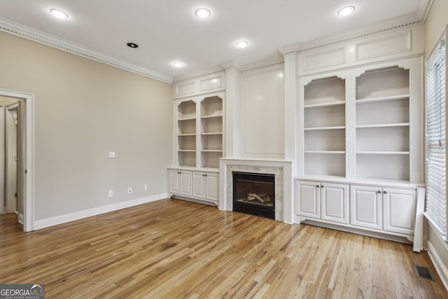 unfurnished living room with crown molding, a high end fireplace, and light wood-type flooring