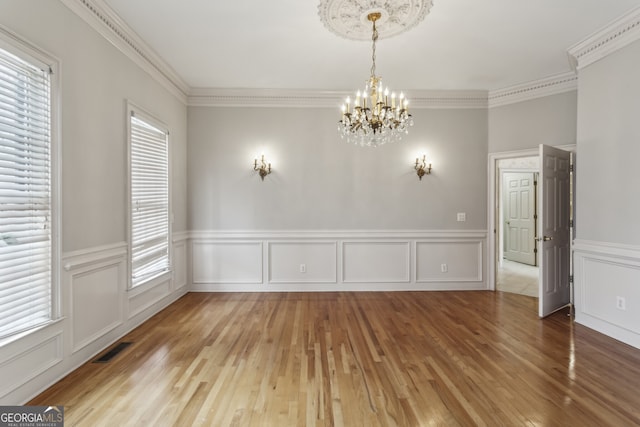 unfurnished room with ornamental molding, wood-type flooring, and a chandelier