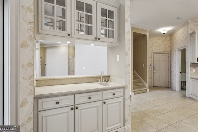 kitchen with crown molding, light tile patterned floors, sink, and white cabinets