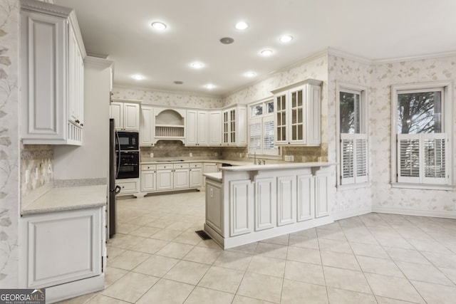 kitchen with ornamental molding, black appliances, kitchen peninsula, and white cabinets