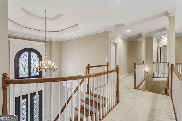 hall with an inviting chandelier, light colored carpet, ornamental molding, and a raised ceiling