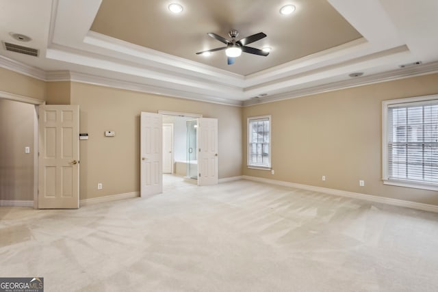 unfurnished bedroom with crown molding, light carpet, and a tray ceiling