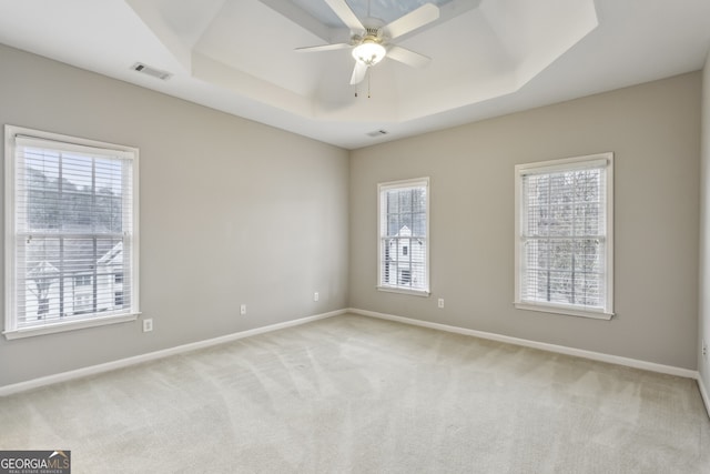 carpeted empty room with ceiling fan and a tray ceiling