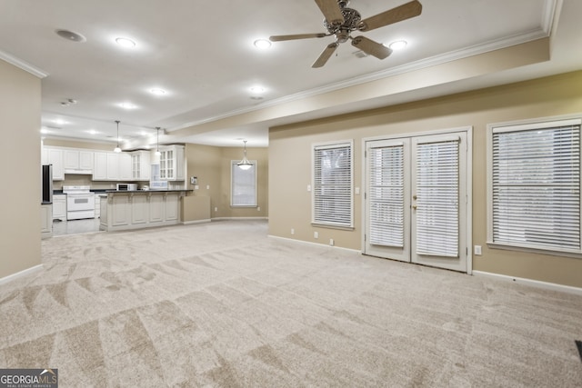 unfurnished living room featuring crown molding, light colored carpet, ceiling fan, and french doors