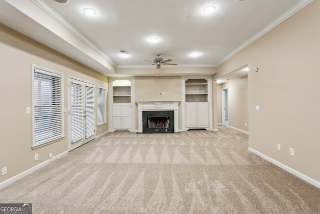 unfurnished living room featuring crown molding, ceiling fan, a fireplace, and light carpet