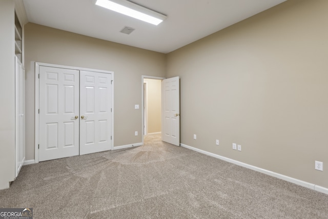 unfurnished bedroom with light carpet and a closet