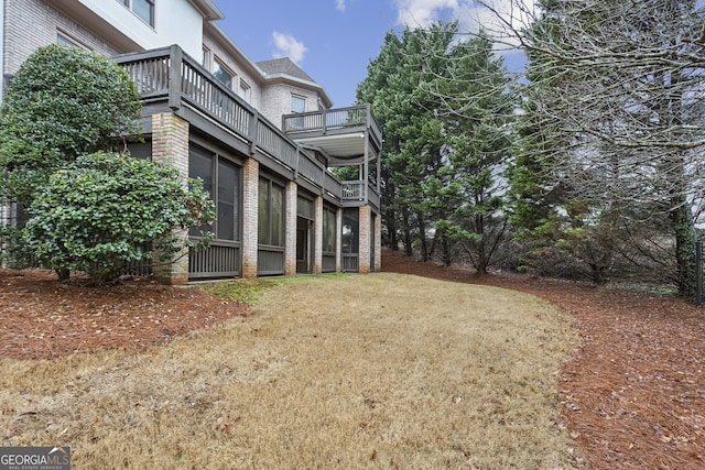 view of side of home featuring a lawn and a balcony