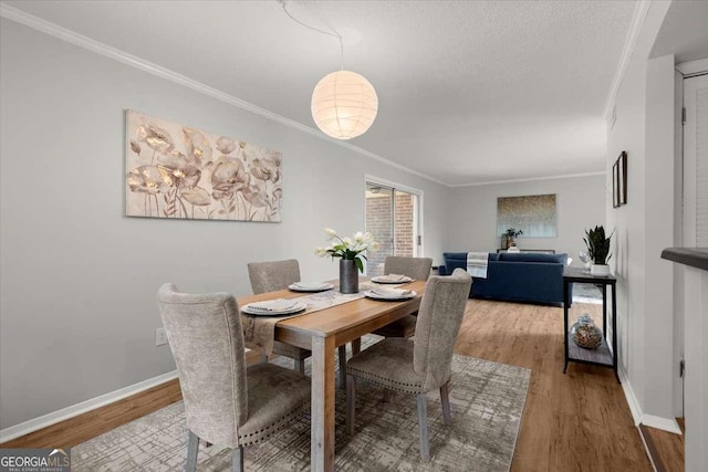 dining space featuring crown molding, a textured ceiling, and light hardwood / wood-style floors