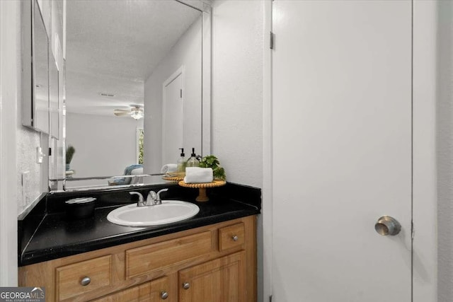 bathroom with ceiling fan, vanity, and a textured ceiling