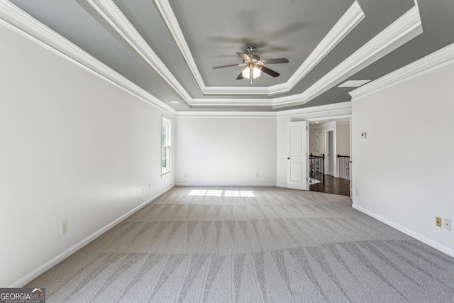 carpeted spare room featuring crown molding, a raised ceiling, and ceiling fan