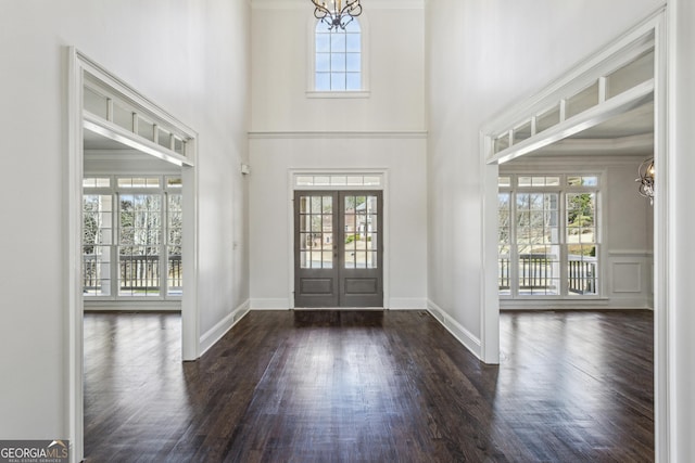 entrance foyer featuring a notable chandelier, a towering ceiling, dark wood-type flooring, and french doors