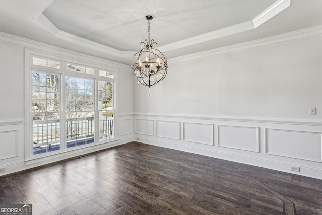 spare room featuring ornamental molding, dark wood-type flooring, a chandelier, and a tray ceiling