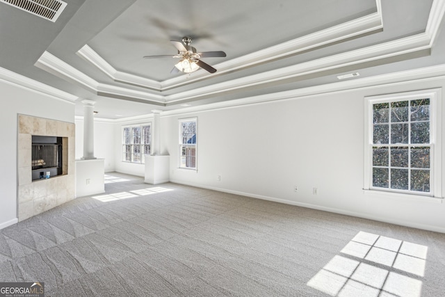 unfurnished living room with a raised ceiling, light carpet, a tile fireplace, and ornate columns