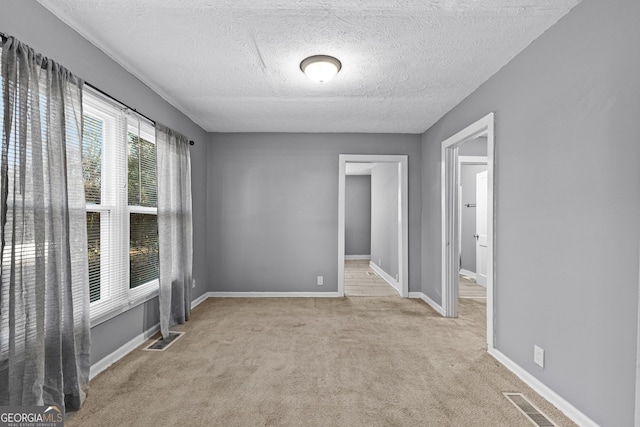 empty room featuring light carpet and a textured ceiling