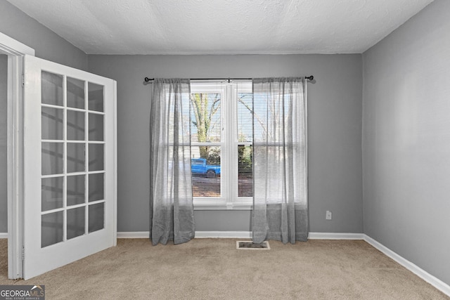 empty room featuring light colored carpet and a textured ceiling