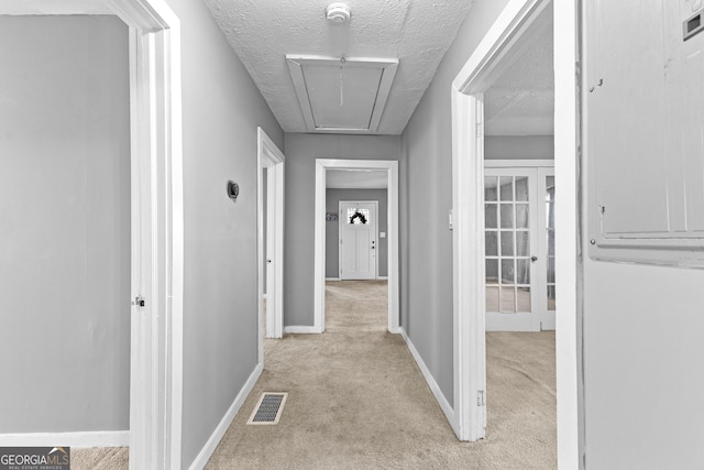 hall featuring light carpet and a textured ceiling