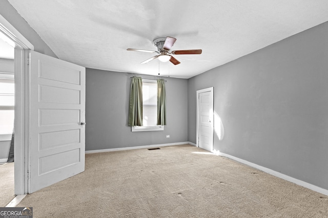 unfurnished bedroom with ceiling fan, light colored carpet, and a textured ceiling