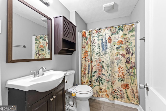 bathroom with walk in shower, vanity, toilet, and a textured ceiling