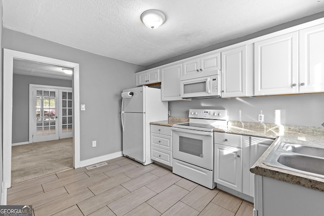 kitchen with sink, white appliances, a textured ceiling, and white cabinets