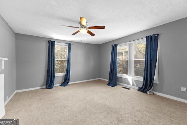 carpeted empty room featuring a wealth of natural light, a textured ceiling, and ceiling fan