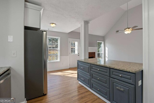 unfurnished living room with hardwood / wood-style flooring, vaulted ceiling, a brick fireplace, and ceiling fan