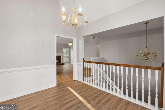 spare room featuring vaulted ceiling, hardwood / wood-style floors, and a notable chandelier