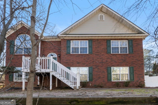 rear view of house with brick siding and stairs