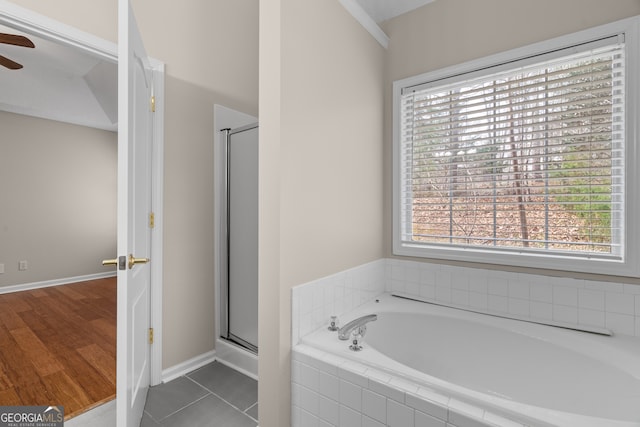 bathroom featuring tile patterned flooring, a shower stall, baseboards, ceiling fan, and a bath