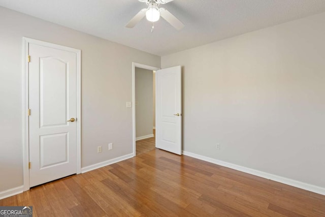 unfurnished bedroom featuring baseboards, wood finished floors, and a ceiling fan