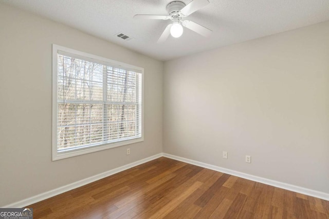 spare room featuring a ceiling fan, wood finished floors, visible vents, and baseboards