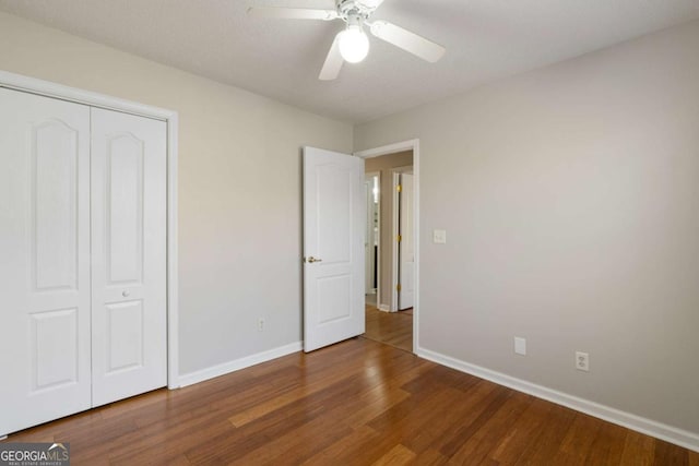 unfurnished bedroom featuring a closet, baseboards, wood finished floors, and a ceiling fan