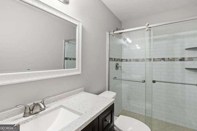 bathroom featuring toilet, a stall shower, vanity, and a textured ceiling