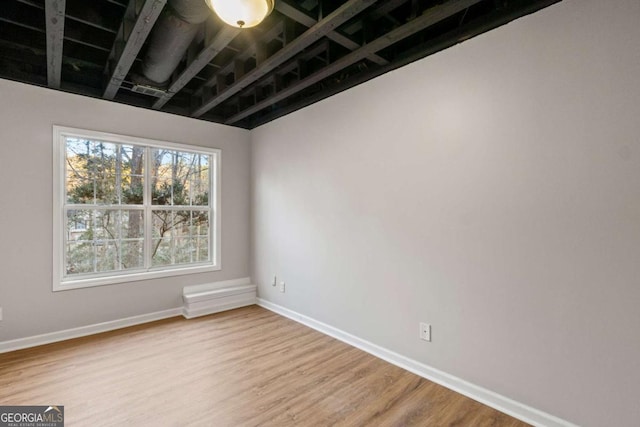 spare room with baseboards and wood finished floors