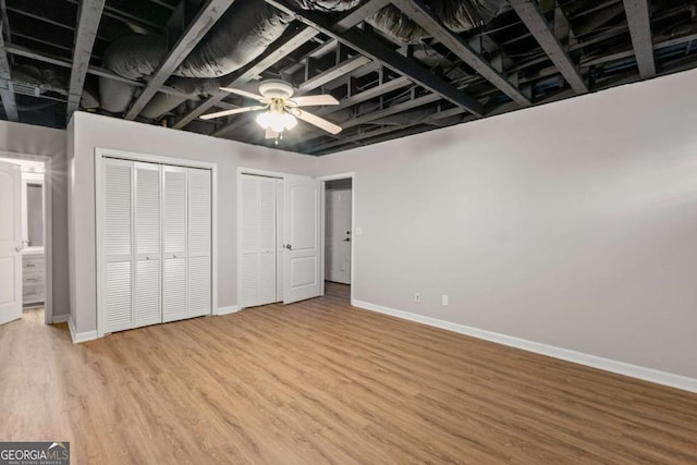 unfurnished bedroom featuring light wood finished floors, baseboards, multiple closets, and a ceiling fan