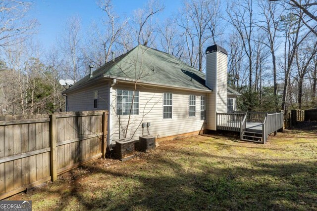 rear view of house with a wooden deck and a lawn