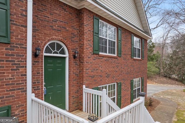 view of exterior entry featuring concrete driveway and brick siding