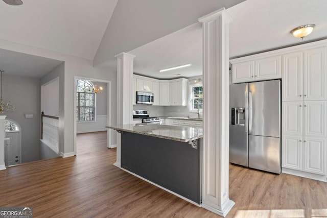 kitchen with sink, light stone counters, appliances with stainless steel finishes, hardwood / wood-style floors, and white cabinets