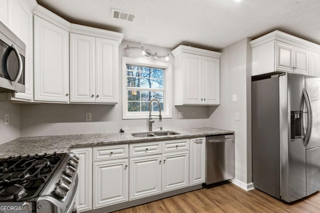 kitchen with appliances with stainless steel finishes, plenty of natural light, decorative columns, white cabinets, and light stone countertops