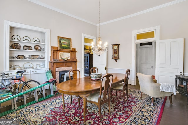 dining room with an inviting chandelier, hardwood / wood-style floors, built in shelves, and ornamental molding