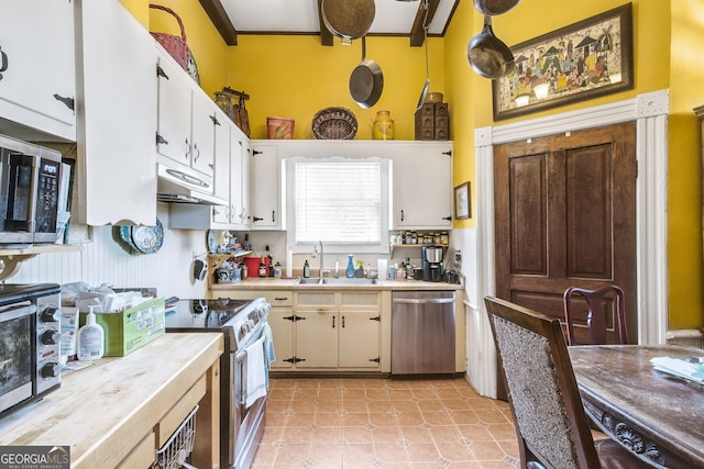 kitchen featuring white cabinetry, appliances with stainless steel finishes, sink, and decorative light fixtures