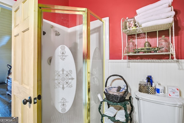 bathroom featuring toilet and a shower with shower door