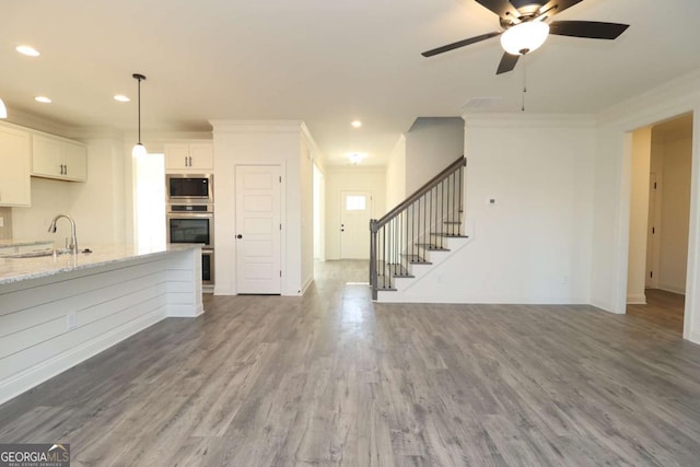 kitchen with sink, white cabinetry, crown molding, stainless steel appliances, and light stone countertops