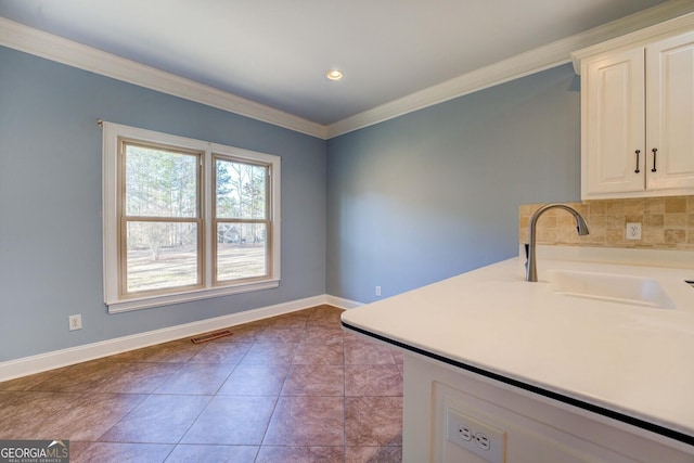 kitchen featuring tasteful backsplash, white cabinetry, sink, light tile patterned floors, and crown molding