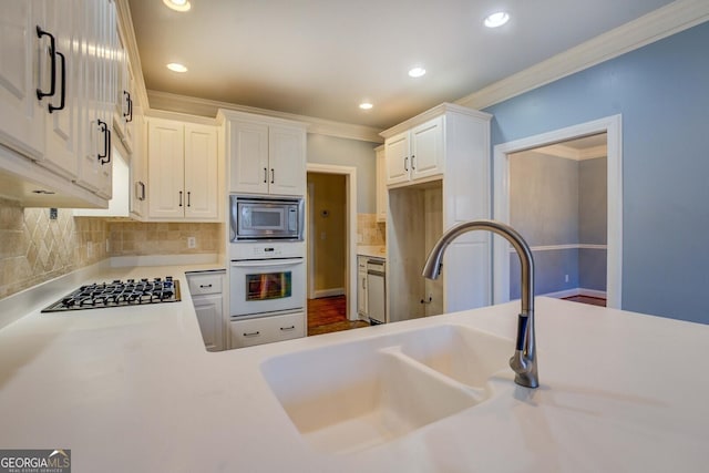 kitchen with crown molding, appliances with stainless steel finishes, decorative backsplash, and white cabinets