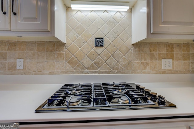 kitchen with stainless steel gas stovetop, white cabinets, and backsplash