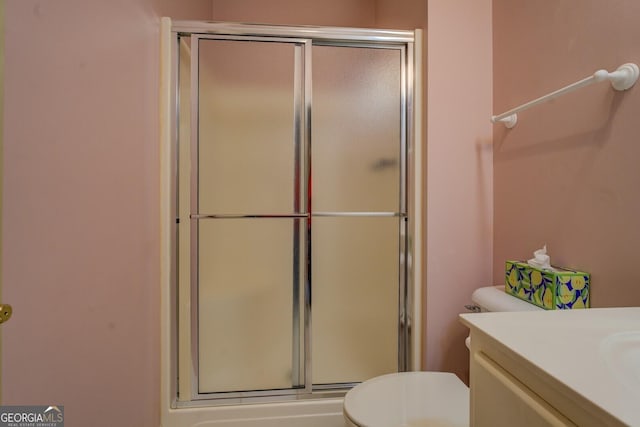 bathroom featuring vanity, toilet, and a shower with shower door