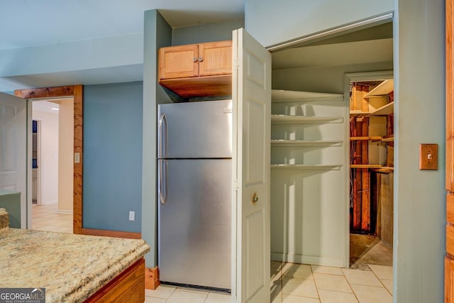 kitchen featuring stainless steel refrigerator, light brown cabinets, and light tile patterned floors